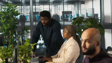 Çalışma arkadaşları masadaki bilgisayar ekranında veri tablolarını inceliyor. Masaüstü bilgisayarındaki hesap tablolarını tamamlayan çalışanlardan oluşan bir ekip verileri giriyor ve analiz ediyor, kamera A