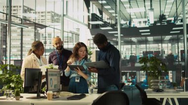 Çok ırklı iş arkadaşları çeşitli ofislerdeki tabletlerin gelir rakamlarına bakıyorlar. Çok ırklı iş arkadaşları beyin fırtınası yapıyor, şirketin istatistiksel rakamlarını karşılaştırıyor, işi bitirmek için çok çalışıyor, kamera B