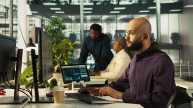 Çalışma arkadaşları masadaki bilgisayar ekranında veri tablolarını inceliyor. Masaüstü bilgisayarında hesap tablolarını tamamlayan çalışanlardan oluşan bir ekip, verileri giriyor ve analiz ediyor, kamera B