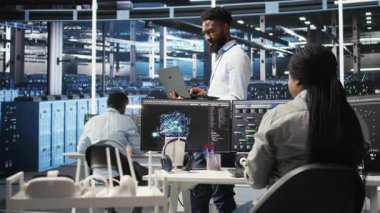 Neşeli veri merkezi mühendisinin portresi düğüm ağacı araçları kullanarak vites sorunlarını analiz ediyor. Afro-Amerikan sunucu merkezi uzmanı. Sistem sağlığını optimize etmek için yapay zeka görselleştirmesi kullanıyor. Kamera A