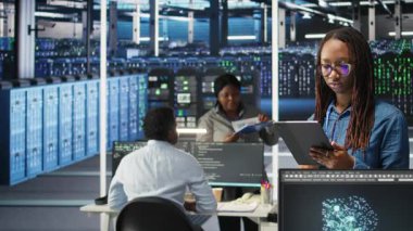 Gülümseyen sunucu odası mühendisinin portresi yapay zeka veri analizi grafiklerini yorumlamak için bir cihaz kullanıyor. Sistem ölçümlerini gösteren yapay zeka aracı kullanan mutlu veri merkezi çalışanı, kamera A