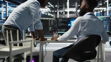 Sunucu merkezi yöneticisi yapay zeka veri analizi grafiklerini kontrol ediyor, çalışanı tebrik ediyor. Veri merkezi ekip lideri, yapay zeka kullanarak yöneticisiyle yumruk tokuşturuyor. Sistem ölçümlerini, kamera A 'yı gösteriyor.