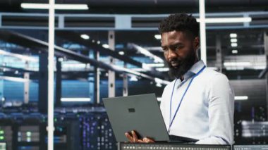 Neşeli veri merkezi mühendisinin portresi düğüm ağacı araçları kullanarak vites sorunlarını analiz ediyor. Sistem sağlığını optimize etmek için yapay zeka görselleştirme bilgilerini kullanan neşeli Afrika kökenli Amerikan sunucu merkezi uzmanı, kamera B