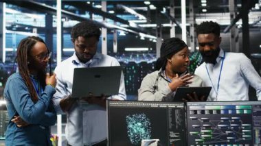 Sunucu tesisinde çalışan gülümseyen veri merkezi uzmanlarının portresi, verileri analiz etmek için düğüm ağacı yazılımı kullanıyor. Mutlu takım vites performansını arttırmak için görsel programlama kullanıyor, kamera B