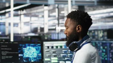 Veri merkezi sistem yöneticisi donanımı yapılandırmak için yapay zeka sinir ağı modelleri kullanıyor. Çalışan, sunucu odasında makine öğrenme programlama dili, sistem işlevselliğinin optimizasyonu, kamera B üzerinde çalışır.