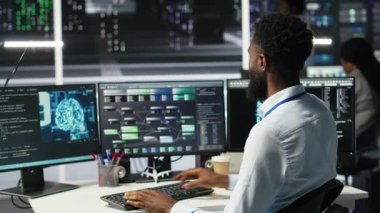 Donanımı yapılandırmak için yapay zeka sinir ağı modelleri kullanan veri merkezi yöneticisi. Adam sunucu odasında yapay zeka programlama dili üzerinde çalışıyor, sistem işlevselliğini optimize ediyor, kamera B