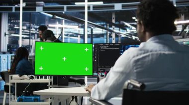 Parapleji yapan veri merkezi mühendisi yeşil ekrandaki yapay zeka öğrenme algoritmalarını kullanarak veri tabanlarını analiz ediyor. Krom anahtar bilgisayarında sunucu odası çalışanı yapay zeka ağları kullanıyor. Kamera A.