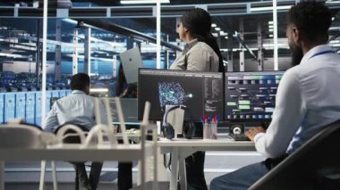 Düz ağaç programlaması yapmak için dizüstü bilgisayar kullanan veri merkezi yönetimi, kaynak tahsisini optimize ediyor. Sunucu odasındaki kadın, bakım planlama için öngörücü yapay zeka görselleştirme sistemleri kullanıyor, kamera A