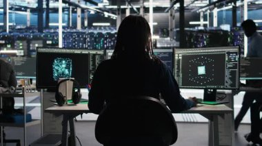 Yapay zeka analizi grafiklerini yorumlayan sunucu odası programcısı, kulaklık takıyor. Veri merkezi bilişim uzmanı sistem ölçümlerini, dinleme müziğini ve kamera A 'yı gösteren yapay zeka aracı kullanıyor.