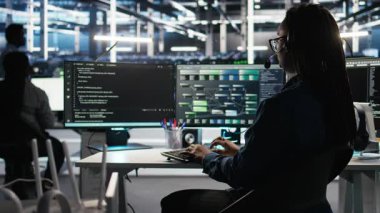 Veri Merkezi çalışanı, bildirilen sorunları gidermek için ses kulaklığı ve görsel programlama paneli kullanıyor. Sunucu çiftliği teknisyeni düğüm ağacı arayüzüne bakıyor, mikrofonla konuşuyor