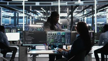 Veri merkezi yöneticisi verileri analiz etmek için düğüm ağacı yazılımı kullanan teknisyeni denetliyor. Sunucu odası ekip lideri IT uzmanını vites performansını arttırmak için görsel programlama araçları kullanarak denetliyor, kamera A