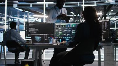 Sunucu merkezi yöneticisi sistem sağlığını optimize etmek için düğüm ağacı yazılımı kullanarak programcıyla konuşuyor. Veri Merkezi Yöneticisi, Yapay Zeka görselleme, Kamera A kullanarak ekipman sorunlarını analiz eden bilişim uzmanı.