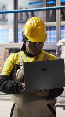 Güvenilirliği sağlamak için otomatik sistemleri test eden gülümseyen akıllı fabrika uzmanı. Endüstri 4.0 endüstriyel santralindeki mutlu mühendis dar boğazları tanımlıyor ve donanımı optimize ediyor