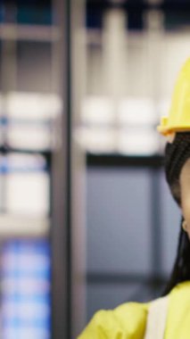 Dikey video güneş panelleri makine sistemlerini denetlemek için dizüstü bilgisayar kullanan bitki mühendisliği ekibi. Photovoltaics fabrikası çalışma arkadaşları işlemleri sürdürmek için defter üzerinde yazılım kullanın, kamera B