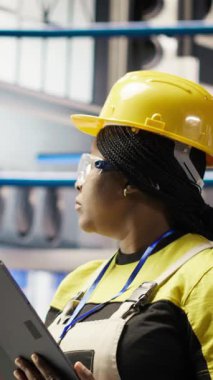 Akıllı fabrikada gülen bir mühendis tablet kullanarak, IoT sensör verilerini analiz ederek öngörü onarımı yapıyor. Fotovoltaik 'in işlevsel güvenilirliğini yöneten endüstriyel fabrika işçisi