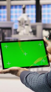 Dikey video güneş panelleri bitki teknisyeni sistemleri denetlemek için yeşil ekran tableti kullanıyor. Fotovoltaik fabrikası çalışanı, işlemleri sürdürmek için krom anahtar aygıtı üzerinde yazılım kullanır. Kamera A: