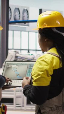 Dikey video Akıllı güneş panelleri fabrika mühendisliği ekibi dizüstü bilgisayarla üretim hatlarını denetliyor. Takım çalışması sektörü 4.0 fabrika çalışanları makinelerin en uygun verimlilikte çalışmasını sağlar