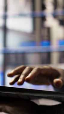 Otomatik sistemleri test etmek ve üretim ölçümlerini izlemek için dizüstü bilgisayar kullanan akıllı fabrika işçisinin dikey videosu. Sektör 4.0 tesis uzmanı, arızaları tespit etmek ve düzeltmek için makineleri denetliyor