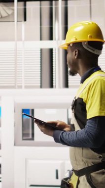 Dikey video servisi elinde tablet, fabrikada yürüyor, sistemleri denetliyor, ekipmanların en uygun verimlilikte çalışmasını sağlıyor. Sanayi fabrikası elektrikçisi tesis altyapısını denetliyor, kamera A