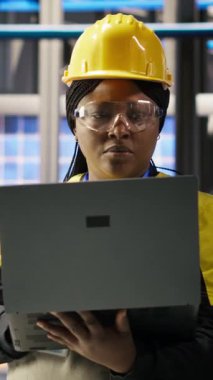 Dikey video güneş panelleri fabrika mühendisi IoT sensörlerinden elde edilen verileri inceliyor. Fotovoltaik durgunluğu azaltmak için sistem kontrolü yapan işçiler