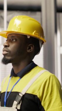 Dikey video teknisyeninin elinde alet çantası var. Fabrikada yürüyor. Güneş paneli üretim hattı ekipmanlarını denetliyor. Otomatik endüstriyel sistemlerdeki fotovoltaik montaj sistemlerini koruyan mühendislik uzmanı