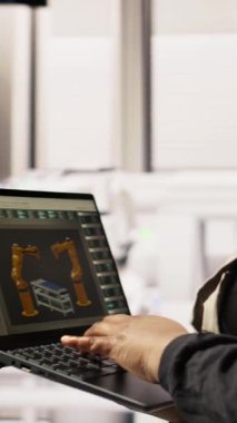 Sürdürülebilir sanayi santralindeki dikey video teknisyeni dizüstü bilgisayar kullanarak üretim ekipmanlarını izliyor ve arızaları teşhis ediyor. Fabrika işçisi, güneş modülü montaj hattındaki tamir görevlerini koordine ediyor