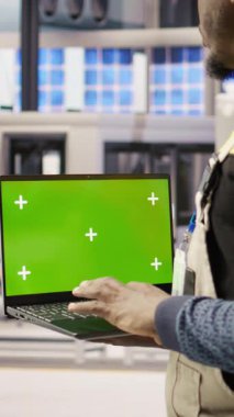 Yüksek teknoloji makinelerini ayarlamak ve sensör verilerini analiz etmek için yeşil ekran dizüstü bilgisayar kullanan dikey video fabrikası mühendisi. Endüstriyel fabrika çalışanı sorun çıkarmak için krom anahtar dizüstü bilgisayar kullanıyor