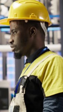 Dikey video akıllı fabrika çalışanı bilgisayar klavyesinde daktilo kullanıyor, otomatik sistemleri test ediyor, bakım yapıyor. Endüstri 4.0 tesis çalışanı, ekipman ve tamir hatalarını incelemek için bilgisayar kullanıyor, kamera B