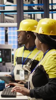 Dikey video akıllı fabrika yöneticisi yüksek teknoloji makinelerini ayarlayan ve sensör verilerini analiz eden bir mühendis tarafından yapılan işleri denetliyor. Takım lideri denetleme mühendisi sorun çözme ekipmanı