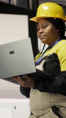 Dikey video akıllı fabrika mekanik bilgisayar işlemleri ve dizüstü bilgisayar kullanarak enerji tüketimini izleme. Sektör 4.0 'da yürüyen tamirci elinde defterle teknik destek sağlıyor.