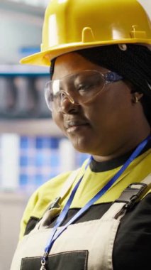 Dikey video akıllı fabrika uzmanı dizüstü bilgisayarda daktilo kullanıyor, güvenilirliğini sağlamak için otomatik sistemleri test ediyor. Sanayi 4.0 fabrika teknisyeni, darboğazları belirlemek ve optimize etmek için dizüstü bilgisayar kullanıyor