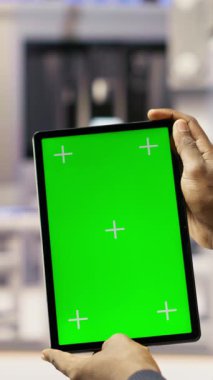 Akıllı fabrikadaki dikey video mühendisi yeşil ekran tableti kullanarak kalite kontrolü sağlayan robot montaj hatlarını denetliyor. İşçi krom anahtar aygıtı kullanarak otomatik taşıyıcı sistemlerini izliyor