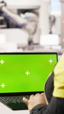 Fotovoltaik fabrikasında sistem performans ölçümlerine bakmak için krom anahtar dizüstü bilgisayar kullanan dikey video mühendisi. Sektör 4.0 santralinde çalışan işçiler enerjiyi izlemek için yeşil ekran modelleme defteri kullanıyorlar