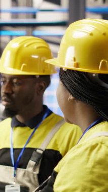 Endüstriyel santralde bilgisayar yazılımını kullanarak arızaları tespit eden dikey video yöneticisi teknisyeni. Fabrika ekip lideri montaj hatlarındaki tamir görevlerini koordine etmek için iş arkadaşıyla birlikte çalışıyor