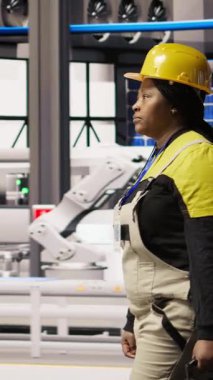 Dikey video tamircisi alet çantasını tutuyor akıllı fabrikada yürüyor, bakım yapmaya hazırlanıyor. Tamirci sektör 4.0 tesisini teftiş ediyor, tamir için ekipman hasarı arıyor, bakım yapıyor.