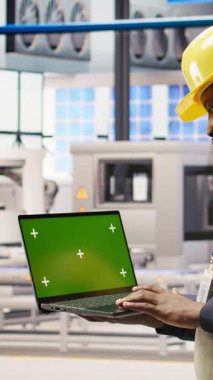 Akıllı fabrikadaki dikey video mühendisi IoT sensör verilerini analiz etmek için yeşil ekran dizüstü bilgisayar kullanıyor. Endüstri 4.0 bitkisel uzmanlık sistemi tanımlaması krom anahtar model defteri üzerinde çalışma süresini azaltmak için