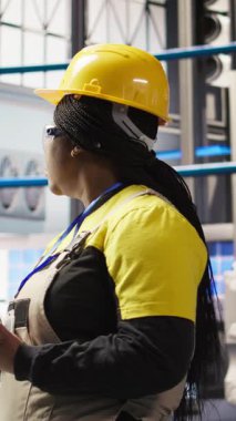 Dikey video Akıllı güneş panelleri fabrika mühendisi üretim hatlarını denetlemek için tablet kullanıyor. Sektör 4.0 fotovoltaik fabrikasındaki kadın makinelerin en uygun verimlilikte çalışmasını sağlar.