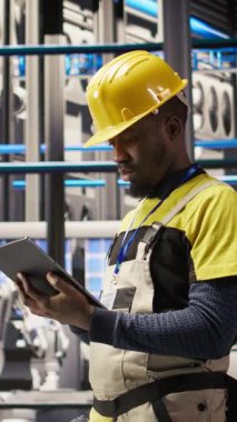 Montaj hatlarını yükseltmeden önce IoT sensörlerinin verilerini analiz etmek için tablet kullanan dikey video akıllı fabrika tamircisi. Endüstri 4.0 fabrika personeli hata ve kameraları azaltmak için sistem kontrolü yapıyor