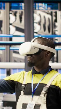 Sanal gerçeklik simülasyonunu kullanarak ekipman arızalarını öngören dikey video akıllı fabrika uzmanı. Sanayi 4.0 fabrika mühendisi bakım prosedürlerini izlemek ve hasar onarmak için VR kulaklık kullanıyor
