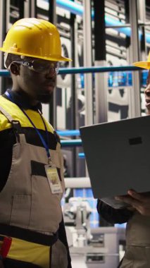 Dikey video mühendisliği ekibi akıllı fabrikada beyin fırtınası yapıyor, IoT sensör verilerini analiz ediyor. Fotovoltaik sistemlerin işlevsel güvenilirliğini yöneten sanayi 4.0 fabrika çalışma arkadaşları