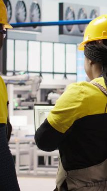 Güneş paneli üretim hattı ekipmanlarını denetleyen dikey video bilişim personeli. Otomatik endüstri 4.0 fabrikasında fotovoltaik montaj sistemleri kuran, beyin fırtınası yapan iş arkadaşları, kamera A