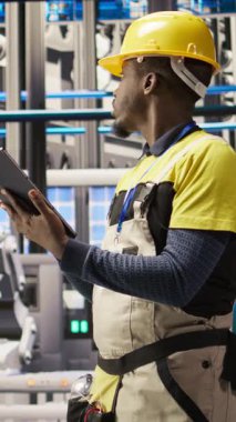 Yeşil enerji çözümleri uygulamak için tablet kullanan dikey video sanayi teknisyeni güneş enerjisini montaj sistemlerine entegre ediyor. Akıllı fabrika işçisi üretim verimliliğini arttırıyor.