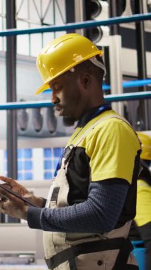 Dikey video akıllı fabrika tamircisi otomatik sistemleri test ediyor, önleyici bakım yapıyor. Endüstri 4.0 tesis tamircisi tespiti ve servis arızalarını tespit etmek için ekipman denetliyor, kamera A