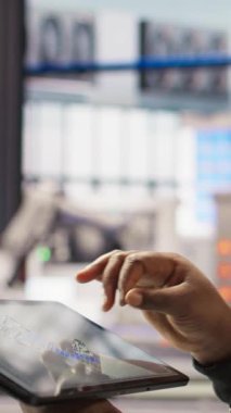 Dikey video endüstrisi 4.0 endüstriyel fabrika mühendisi tablet üzerinde CAD uygulaması kullanarak yeni robotik makineler tasarlıyor. Tesis zemininde ekipman düzenini optimize eden akıllı bir fabrika işçisi, kamera.