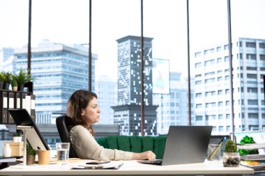 Güçlü nüfuzlu kadın yönetmen, penceresinden şehir manzarasına hayran kalarak ofisinde dinleniyor. Üst düzey çalışma alanında dinlenen kadın yönetici..