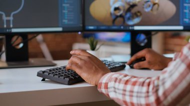 Erkek mühendis CAD yazılımı kullanarak modern endüstriyel arayüzde 3D prototipler tasarlıyor. Uzman, 3 boyutlu modelleme ve teknik uzmanlık yoluyla dişli ve makine araçları üretiyor. Kamera B.