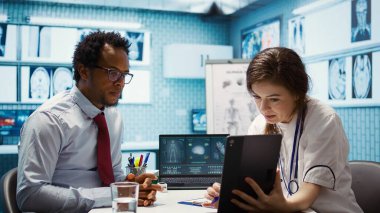 Test bulgularını tablet üzerinde tarama yorumu yoluyla sunan pratisyen hekim tanısal ve olası tedaviyi tartışıyor. Tıbbi uzman hastaya tavsiye verir. Kamera B.