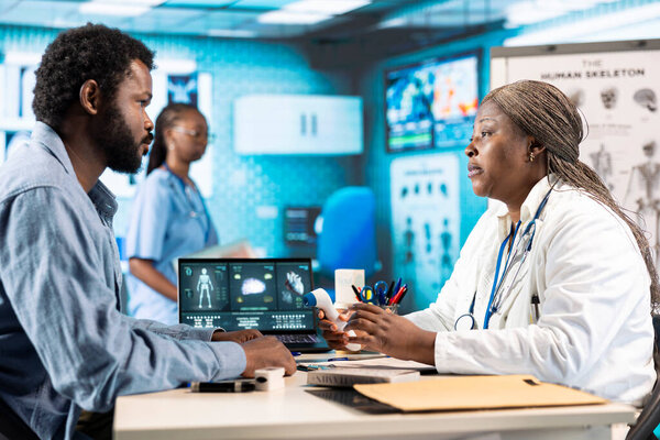 Профессиональная медицинская консультация, демонстрирующая результаты обследования врача и пациента, укрепляющая доверие и точность в отношении здоровья. Черный мужчина и женщина во время осмотра.