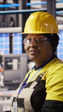 Endüstriyel fabrikadaki gülümseyen teknisyenlerin dikey video portresi güneş enerjisi kurulum sürecini denetliyor. Otomatik robotik kalibre edilen yenilenebilir enerji üretim tesisinde mutlu bir işçi.