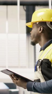 Dikey video servisi elinde tablet, fabrikada yürüyor, sistemleri denetliyor, ekipmanların en uygun verimlilikte çalışmasını sağlıyor. Sanayi fabrikası elektrikçisi tesis altyapısını denetliyor, kamera B